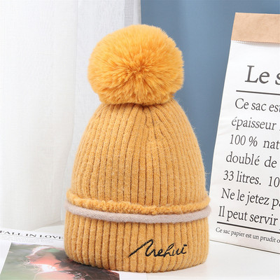 Moderna ženska pletena kapa s pomponom i vezom