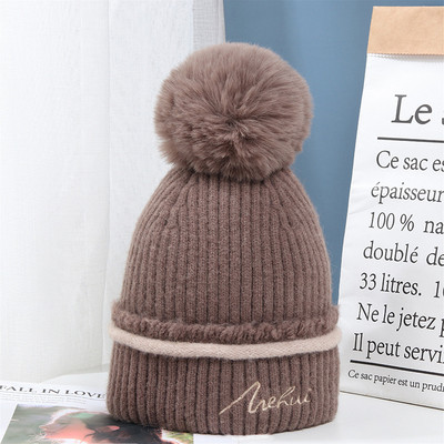 Moderna ženska pletena kapa s pomponom i vezom