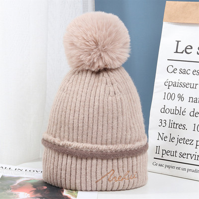 Moderna ženska pletena kapa s pomponom i vezom