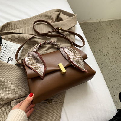 Elegantna ženska torba s metalnom kopčom i vrpcom u boji