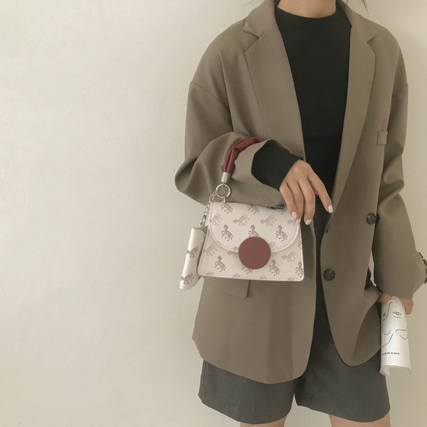 Kis négyzet alakú táska két fogantyúval és nyomattal