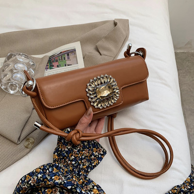 Maza taisnstūra soma, kas dekorēta ar akmeņiem un garu rokturi