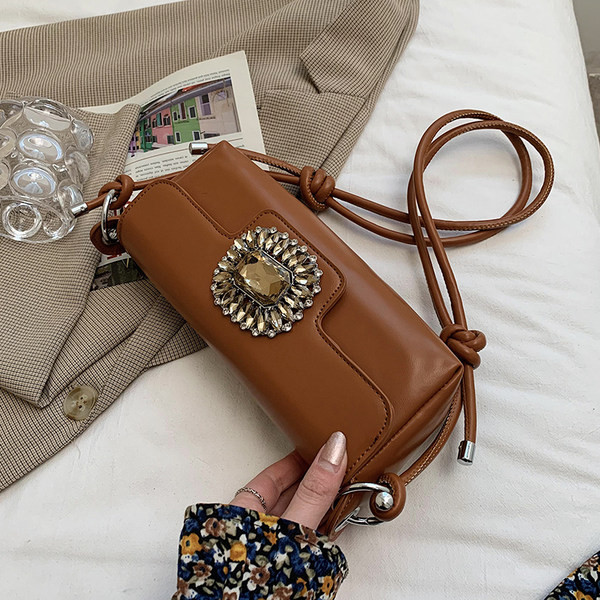 Maza taisnstūra soma, kas dekorēta ar akmeņiem un garu rokturi