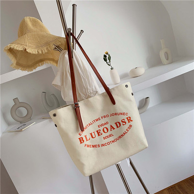 Liela tekstila soma ar eko ādas rokturiem un uzrakstiem