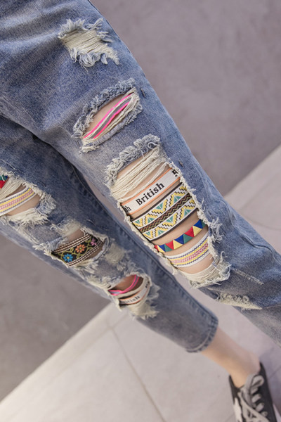 Sieviešu džinsi ar augstu vidukli un izšuvumiem saplēstiem motīviem