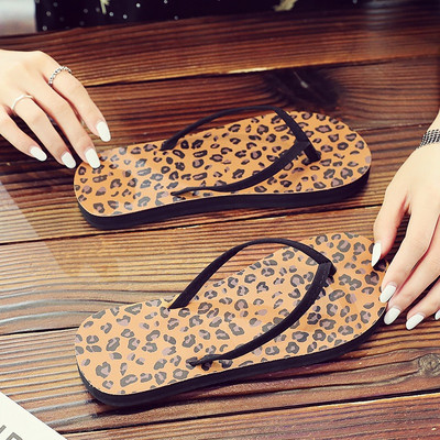 Sieviešu flip flops pāri purngalam uz plakanas zoles, kas piemērota pludmalei