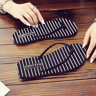 Sieviešu flip flops pāri purngalam uz plakanas zoles, kas piemērota pludmalei