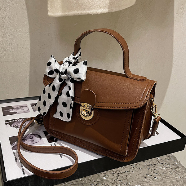 Női bőrtáska két füllel és szalaggal