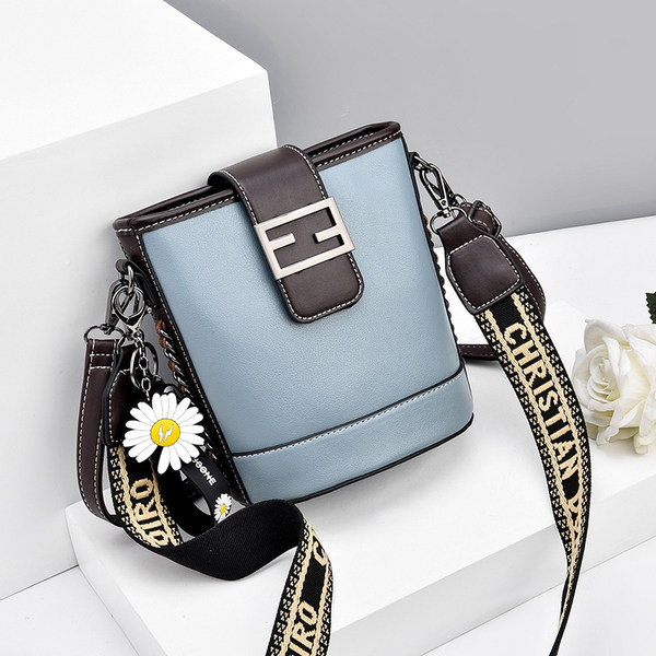 Moderna ženska torba s metalnim kopčanjem i izvezenim natpisom na remenu