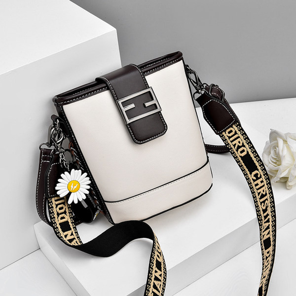 Moderna ženska torba s metalnim kopčanjem i izvezenim natpisom na remenu